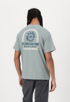 Light green cotton t-shirt featuring a large blue graphic of a sun and eye on the back, with the text "QUIKSILVER SAYS RELAX" below.