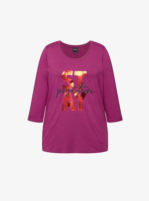 Magentan värinen pitkähihainen t-paita, jossa on avara kaula-aukko ja musta teksti, joka lukee "STAY positive". Kirjaimissa on metallinhohtoinen kuparinvärinen viimeistely.