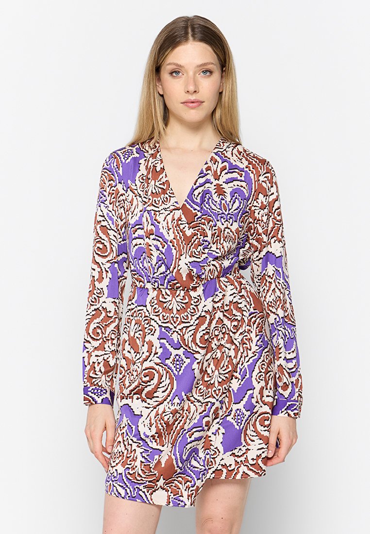 Langsleeve jurk in een bloemenpatroon met paarse, bruine en witte kleuren. De stof heeft een lichte textuur en is voorzien van een wikkeldesign aan de voorkant.