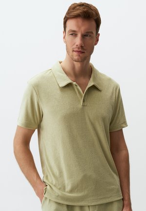 Polo shirt vert olive clair en tissu doux, avec un col classique, des manches courtes et une patte de boutonnage à trois boutons.