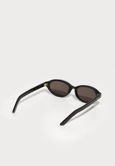 Lunettes de soleil noires avec des verres ronds, en verre teinté marron foncé, et des accents en métal doré sur la monture. Matériau plastique lisse avec un design élégant.