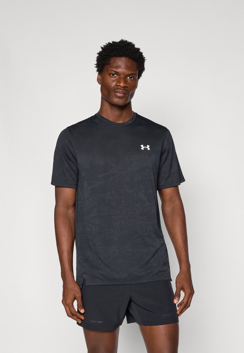 Zwarte sport t-shirt met korte mouwen, textuurstof, subtiel patroon en wit logo op de borst, gecombineerd met zwarte shorts.