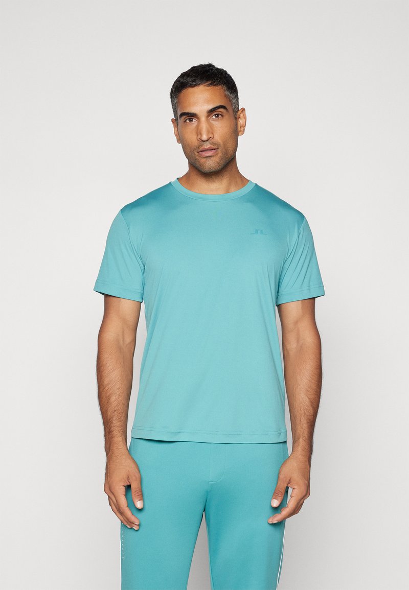 Turkis atletisk t-shirt lavet af letvægtsmateriale med korte ærmer, rund hals og et diskret logo på venstre bryst.