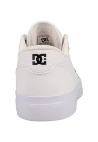 White leather sneaker with a padded cuff, round toe, textured surface, and DC logo in black on the heel. Flat white rubber sole.