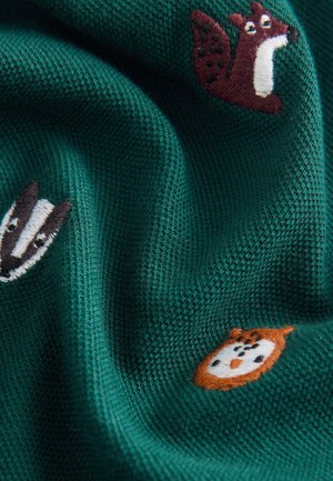 Tessuto verde lavorato a maglia con motivi animali ricamati: uno scoiattolo, un tasso e un gufo in vari colori. La texture appare morbida e accogliente.