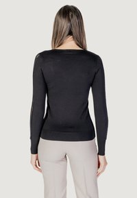 Maglione nero a maniche lunghe con dettagli in pizzo testurizzato lungo le maniche. Design aderente con scollatura rotonda e orlo a costine.