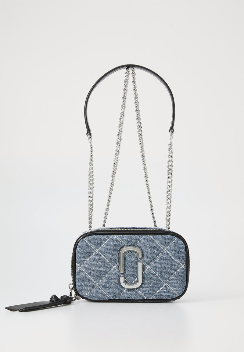 Quilted denim crossbody bag with silver hardware, black leather accents, adjustable chain strap, and zipper closure. Features logo detail.