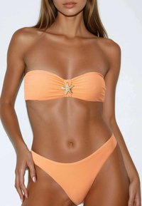 Bikini da donna con top bandeau in arancione chiaro con un accento a forma di stella marina e slip alti dello stesso colore. Texture liscia.