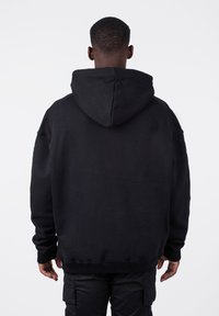 Black oversized hoodie with a hood, long sleeves, and ribbed cuffs and hem. Made of soft fabric with no visible patterns or accents.