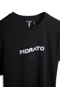 Camiseta de algodón negra con cuello redondo, que presenta un logo bordado en blanco de "MORATO" y un diseño de rosa. Textura suave, corte regular.