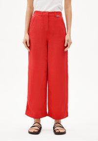Röda byxor med vida ben i lätt tyg, med hög midja och sidofickor. Kombinerat med svarta sandaler med remmar.