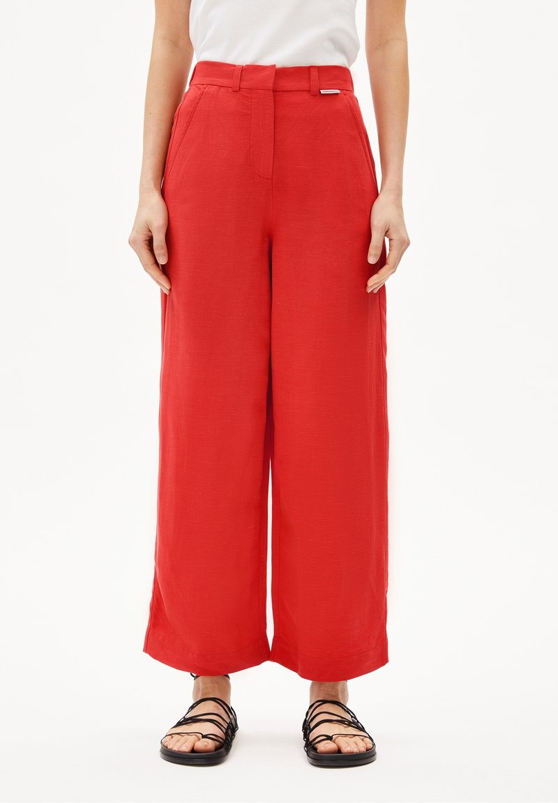 Röda byxor med vida ben i lätt tyg, med hög midja och sidofickor. Kombinerat med svarta sandaler med remmar.