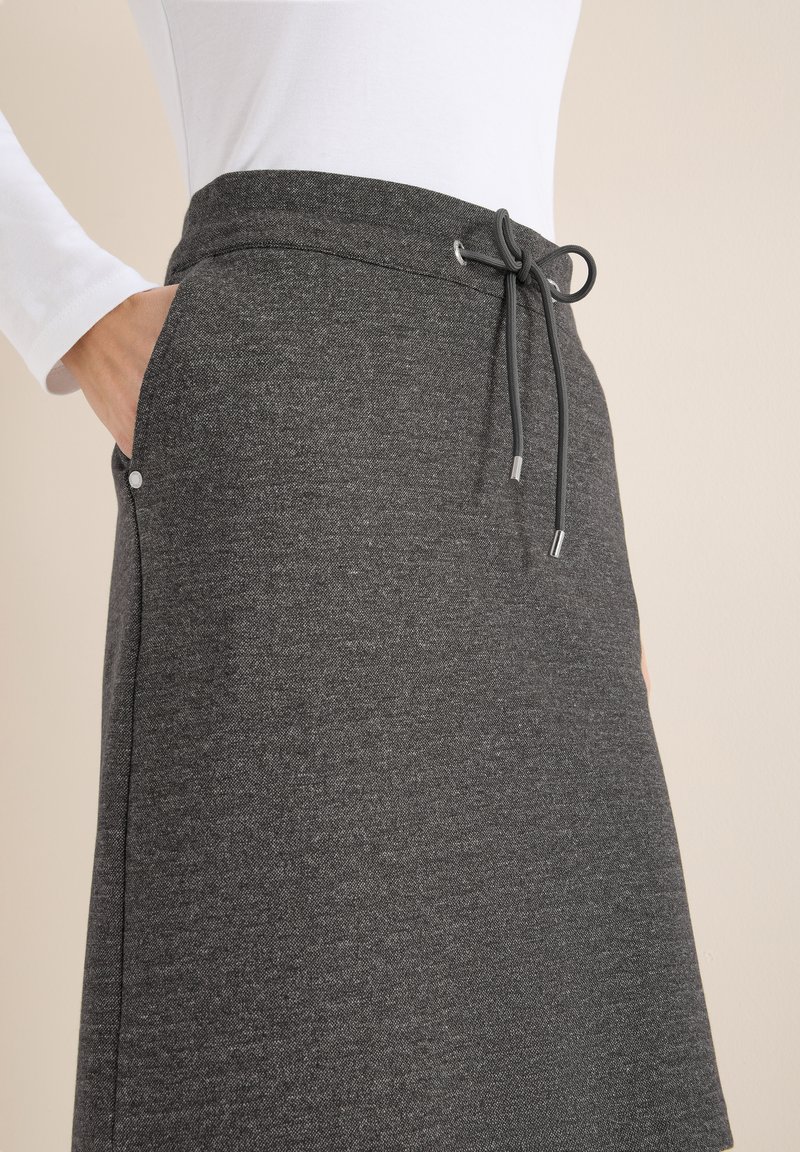 Jupe gris charbon en tissu doux, dotée d'une ceinture élastique avec cordons de serrage et de poches latérales avec des détails discrets en métal.