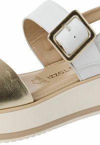 Sandalo con tacco wedge in pelle bianca e dorata, con una grande fibbia dorata e soletta imbottita beige etichettata "Pelle superiore."