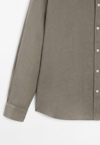 Gray long-sleeve shirt made of a textured fabric, featuring a button-down front, a curved hem, and a standard cuff design.