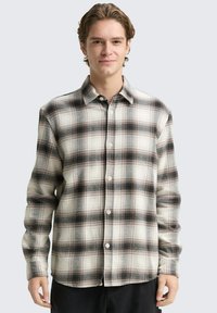 Kariertes Flanellhemd in Creme-, Schwarz- und Rottönen; Knopfdesign; lange Ärmel; weiche Textur; abgerundeter Saum auf Taillenhöhe.