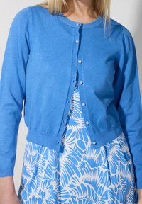 Sininen neulecardigan, jossa on pitkät hihat, pyöreä kaula-aukko ja napitus. Ominaisuudet sileä tekstuuri ja istuva vyötärö.