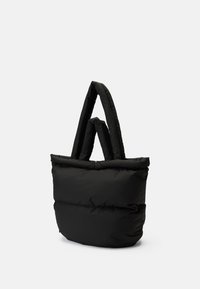 Μαύρη τσάντα tote από πούφερ με απαλή, γεμιστή υφή, φαρδιά επάνω άνοιγμα και δύο επιμηκυμένα χερούλια. Μινιμαλιστικός σχεδιασμός χωρίς ορατό υλικό.