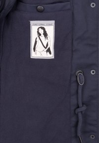 Marine fleecejakke med et syet mærke, der har en illustration og teksten "FUNKTIONEL STRAP", plus en sort snor og trykknap.