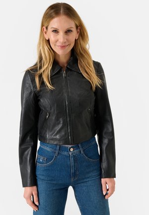 Giacca di pelle nera cropped con colletto classico, chiusura con zip e due tasche laterali, abbinata a jeans in denim blu a vita alta.