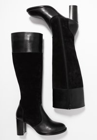 Bottes noires montantes jusqu'aux genoux en combinaison de cuir et de suède. Présentent une tige lisse, un talon bloc et une fermeture à glissière latérale. Accents texturés visibles.