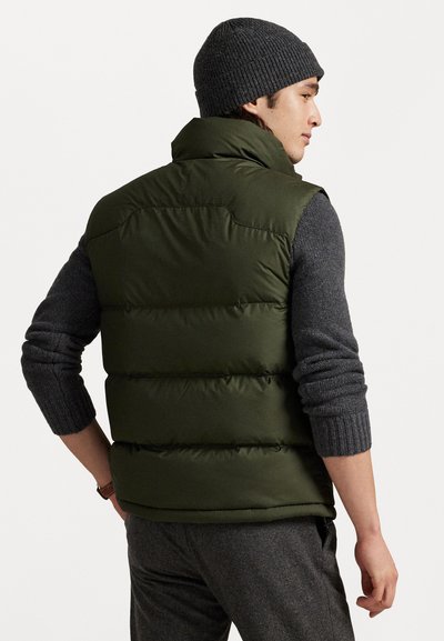 Chaleco verde acolchado con cuello alto y costuras horizontales, usado sobre un suéter de punto gris oscuro. Corte casual, visto desde la parte de atrás.