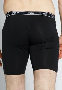 Černé boxerky z elastické bavlny s gumou v pase značky JP1880, mají přiléhavý střih, který končí v polovině stehna. Hladká textura.