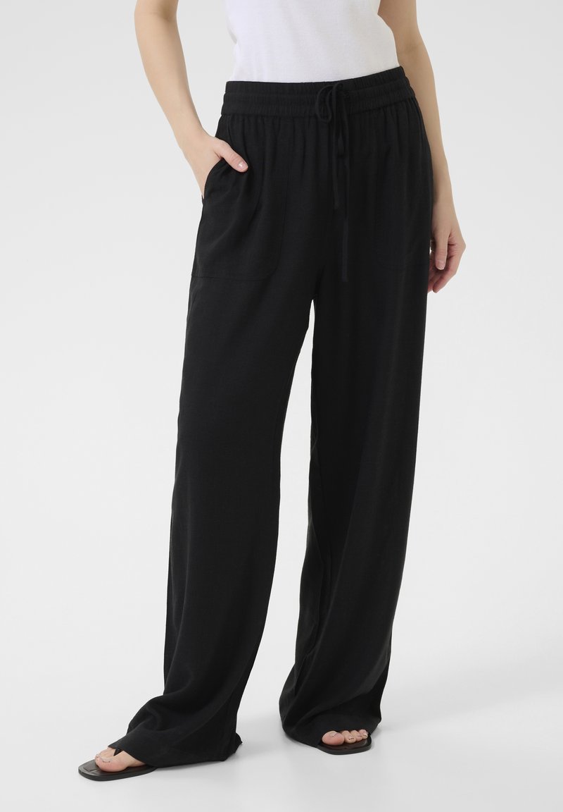 Pantaloni neri larghi realizzati in tessuto morbido con vita elasticizzata, cordoncino regolabile e tasche laterali. Design con gamba svasata.