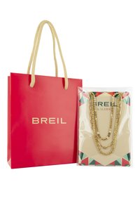 Rød papirpose med "BREIL" logo, der har et struktureret snorhåndtag. Indeni holder en klar pakke lagdelte guldkæder udstillet på en lys baggrund.