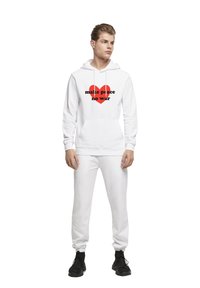 Hvid hættejakke med "make peace" i sort tekst og et rødt hjerte design, parret med matchende hvide sweatpants og sorte sneakers.