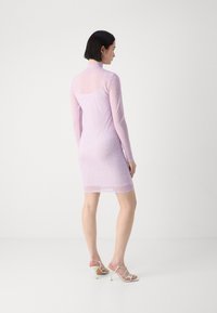 Light pink long-sleeve dress in sheer fabric with a textured pattern; fitted silhouette with a mid-thigh hem and a high neckline.