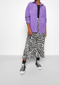 Purple corduroy button-up shirt over a black shirt, paired with a black and white zebra-patterned skirt and black sneakers.