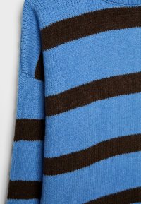 Plava i smeđa prugasta pletena majica s teksturiranim uzorkom, okruglim izrezom i dugim rukavima. Materijal izgleda mekan i udoban.