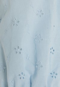 Απαλό μπλε ύφασμα με �κεντημένα λουλουδάτα σχέδια και λεπτομέρειες κοπής. Μαλακή υφή, λεπτή ραφή με ρέουσα εμφάνιση.