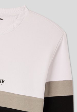 Camicia bianca a maniche lunghe con strisce orizzontali grigie e nere. Collo a coste e materiale in cotone morbido; include branding testuale.