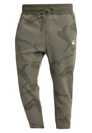 Olivgrüne Jogginghose mit Kordelzug in der Taille, mit pixeligem Tarn- und Karomuster und einem kleinen weißen Logo am rechten Oberschenkel.