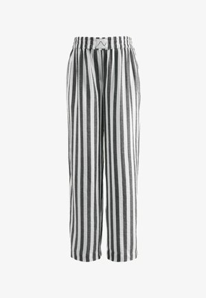 Black and white vertical striped loose-fit pants with elastic waistband and a small stitched label at the front center.