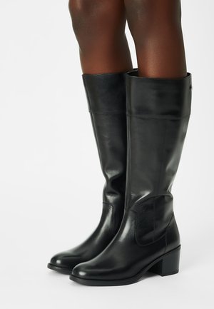Zwarte leren kniehoge laarzen met een gladde textuur, vierkante neus en blokhak. Voorzien van een opgerolde manchet en minimale stikseldetails.