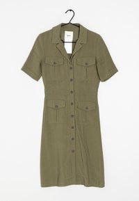 Abito verde oliva con bottoni, maniche corte, due tasche sul petto e una forma aderente. Tessuto liscio con rifiniture in metallo sui bottoni.
