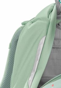 Light green backpack featuring a textured fabric, padded straps, and a smooth silver accent. Includes mesh detailing for breathability.