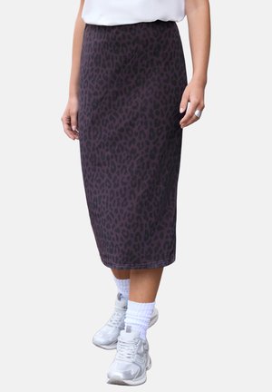 Femme portant une jupe midi à imprimé léopard violet foncé, avec des chaussettes blanches et des baskets blanches, vue de la taille aux pieds.