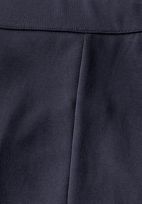 Tissu bleu marine foncé avec une surface texturée, présentant une taille plate et des détails de plis subtils. Coutures cousues le long des bords.