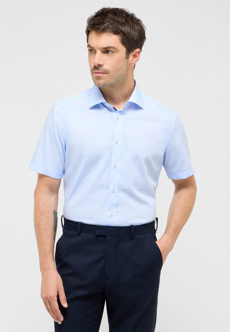 Lichtblauw overhemd met korte mouwen, een puntkraag, knoopsluiting en een subtiele glans. Gecombineerd met donkere broek, in een getailleerde pasvorm.