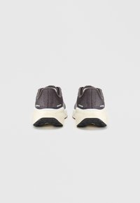 Baskets de sport gris foncé avec une tige en maille, forme arrondie et semelle intermédiaire blanche. Semelle extérieure en caoutchouc noir texturé avec des rainures de traction.