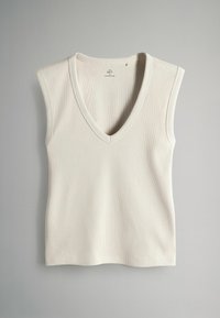 Top de tirantes color crema con canalé, escote en V, mangas cortas y diseño ajustado. Hecho de una tela suave y elástica.