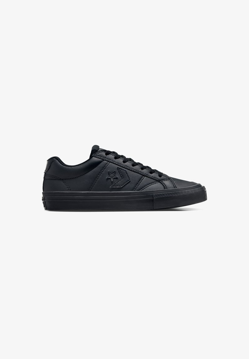 Zapatillas negras de corte bajo, hechas de cuero suave con una suela de goma texturizada, con cordones redondos y un logo de estrella en el lado.