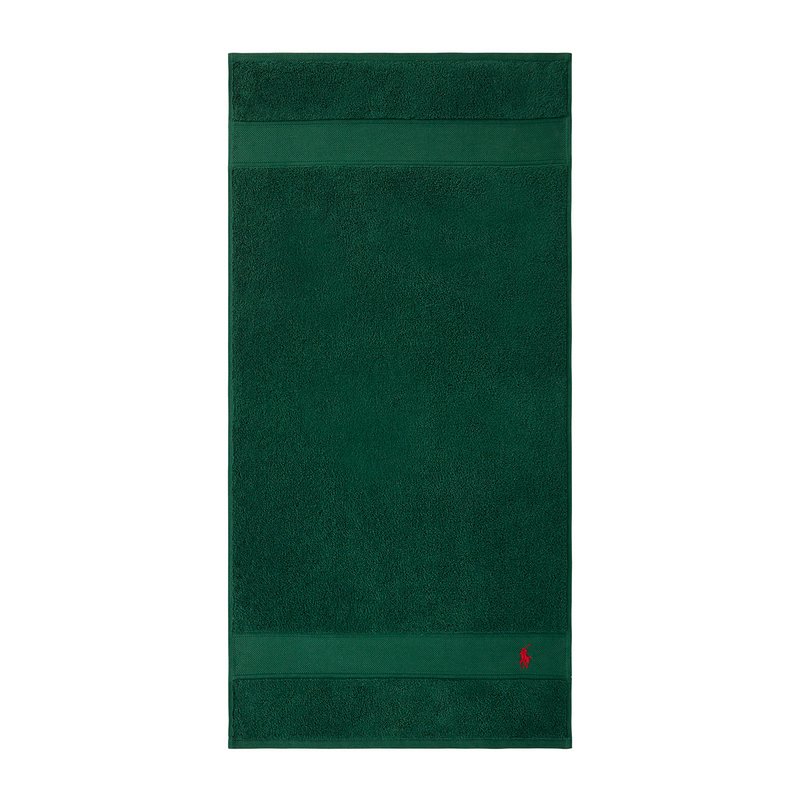 Πράσινη βαμβακερή πετσέτα με υφή, με οριζόντια ρίγα και ένα μικρό κόκκινο λογότυπο στην κάτω γωνία.