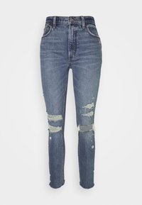 Jeans de mezclilla en azul oscuro con un diseño desgastado, que presentan desgarros deshilachados en las rodillas, estilo de cinco bolsillos y un cierre de botón.