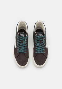 High-top sneakers with a brown suede upper, white rubber sole, and green and black patterned laces. Includes a padded collar and logo tag.