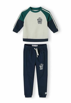 Dwuczęściowy strój dziecięcy składający się z kremowej, zielonej i granatowej bluzy z nadrukiem "NYC State 1997" oraz granatowych spodni dresowych ze ściągaczem i białym napisem.